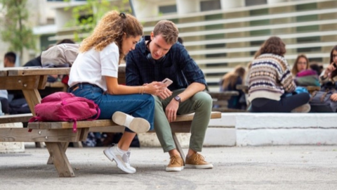 Dos estudiants de la facultat consultant el mòbil